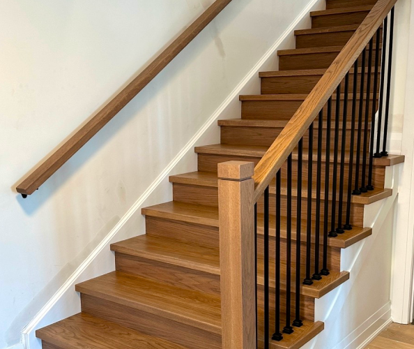 wooden staircase with posts and handrail attached to the wall